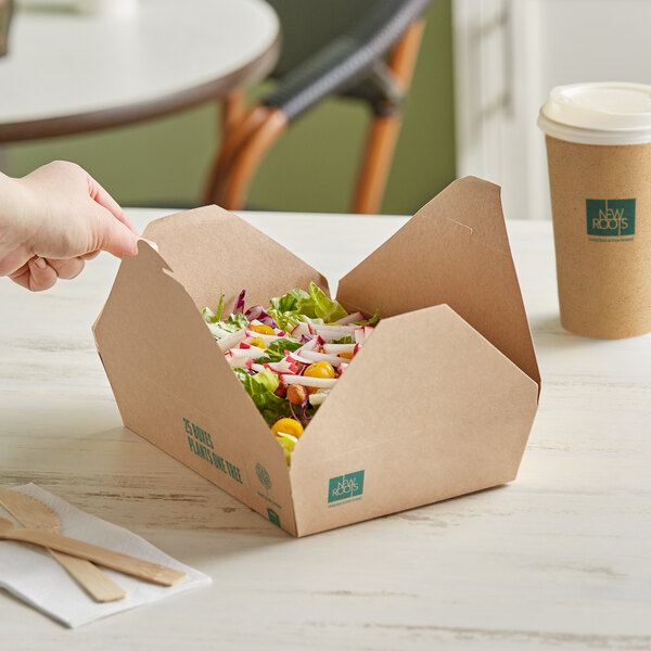 A hand reaching out to take out a salad in a New Roots Kraft PLA-lined take-out box.