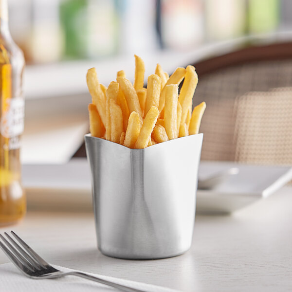 A Tablecraft triangular stainless steel cup filled with french fries on a table.