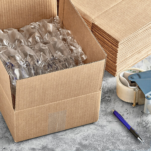 A Lavex shipping box with plastic wrap inside next to a stack of cardboard boxes and a pen.