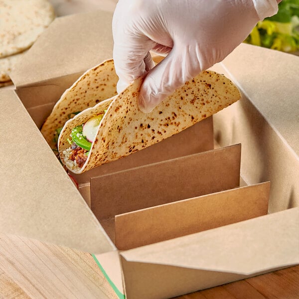 A person wearing a glove holds a tortilla inside a 4-compartment taco holder.