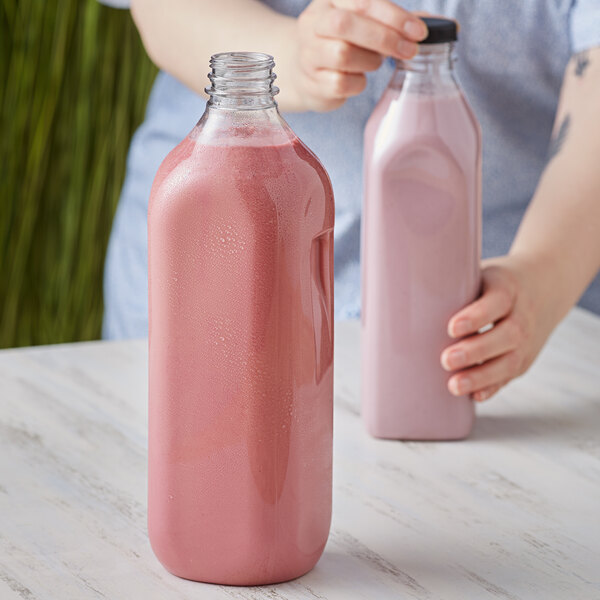 A woman pouring pink liquid into a customizable PET clear square milk bottle.