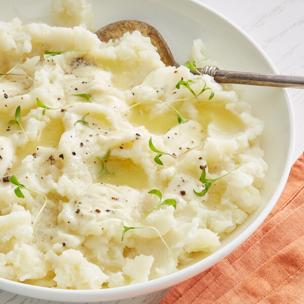 A bowl of mashed potatoes with Urbani Black Truffle Butter and a spoon.