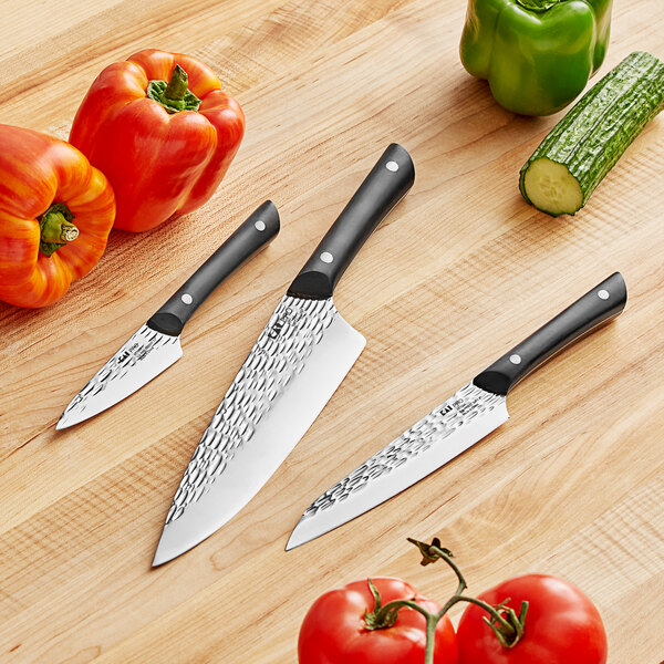 A Kai PRO knife set with three knives next to vegetables on a table.