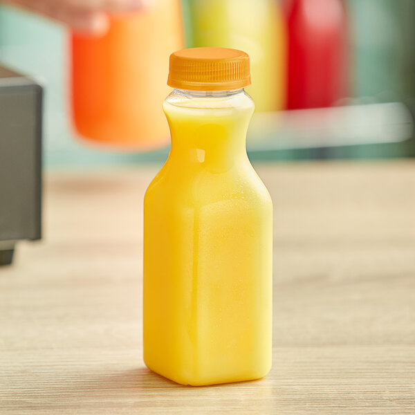 A 10 oz. Square Carafe PET Clear Juice Bottle of orange juice on a table.