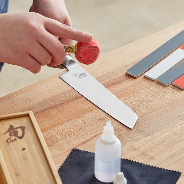 A person using a Shun knife to cut colorful paper.