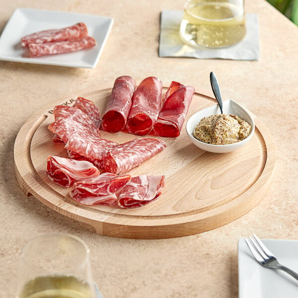 A Boska beech wood serving board with meat and wine on a table.