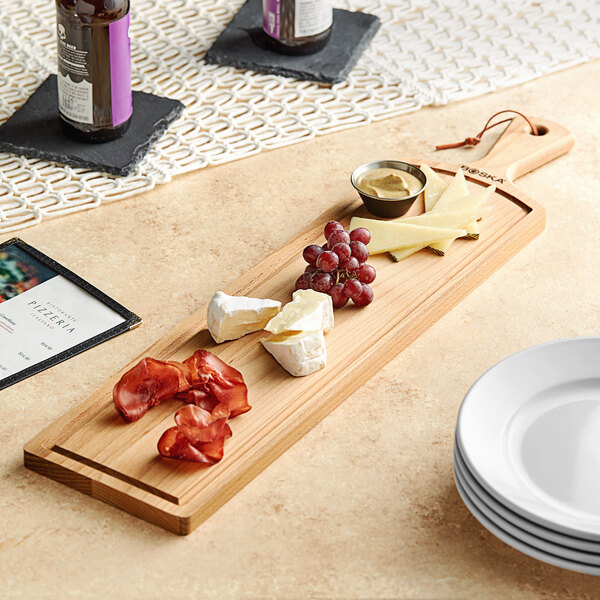 A Boska beech wood serving board with different types of cheese and grapes on a table.