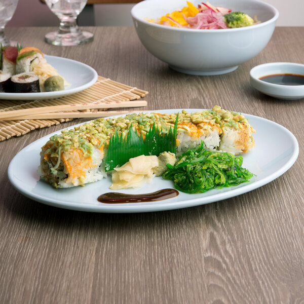 A Blue Jade melamine platter with sushi and green seaweed on a table.