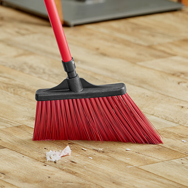 A red Lavex broom head on a wooden floor.
