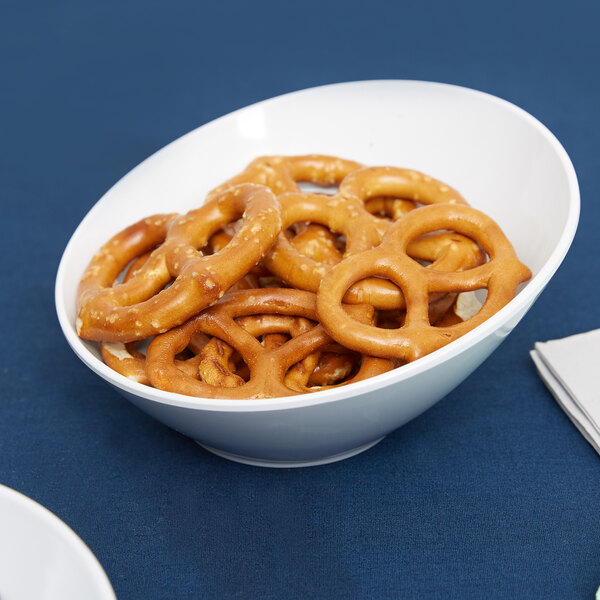 A white San Michele slanted melamine bowl filled with pretzels on a table.