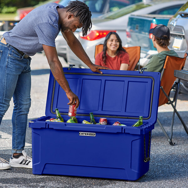 A man opening a CaterGator navy cooler to put a bottle inside.