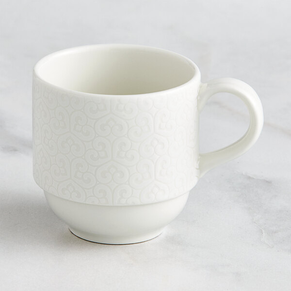 A RAK Porcelain ivory coffee cup with an embossed pattern and a handle on a white background.