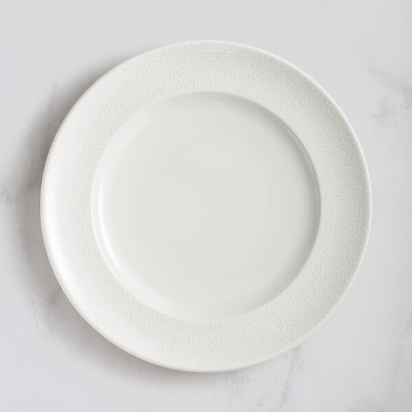 A close up of a RAK Porcelain ivory flat plate with an embossed speckled pattern.