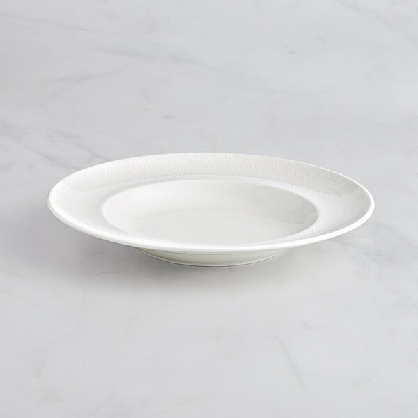 A RAK Porcelain ivory embossed deep plate on a marble surface.