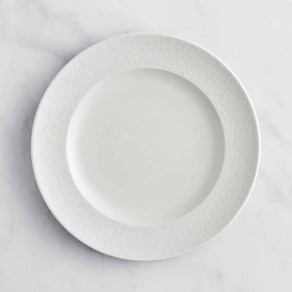 A RAK Porcelain ivory flat plate with an embossed rim.