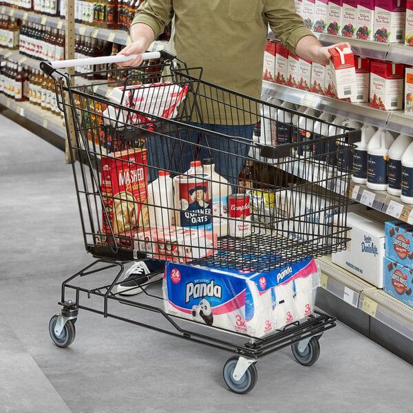 A man pushing a Regency Supermarket black shopping cart in a grocery store aisle.
