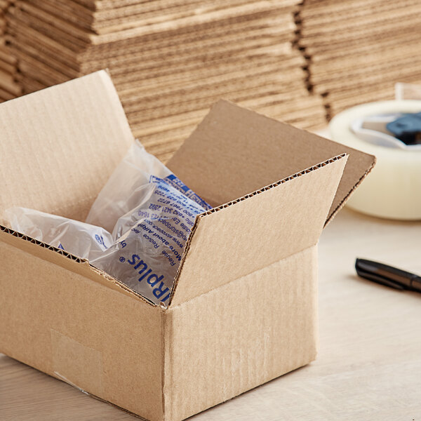 A Lavex kraft cardboard shipping box with clear plastic bag inside and a pen.