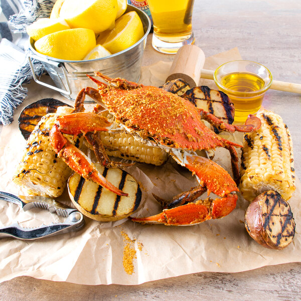A Chesapeake blue crab on a plate of corn, potatoes, and lemons with a nutcracker and a bucket of lemons.