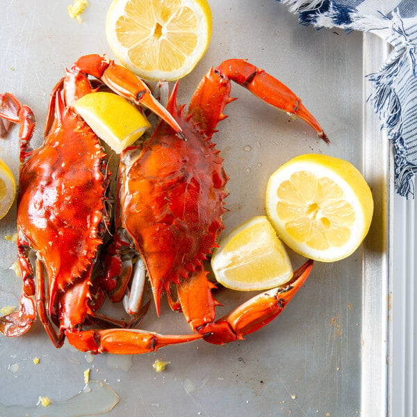 A tray with two steamed blue crabs and lemon wedges.