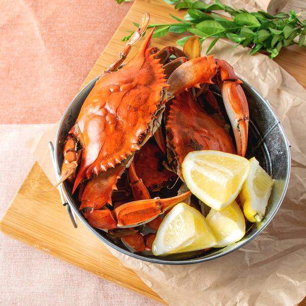 A bowl of live blue crabs with lemons.