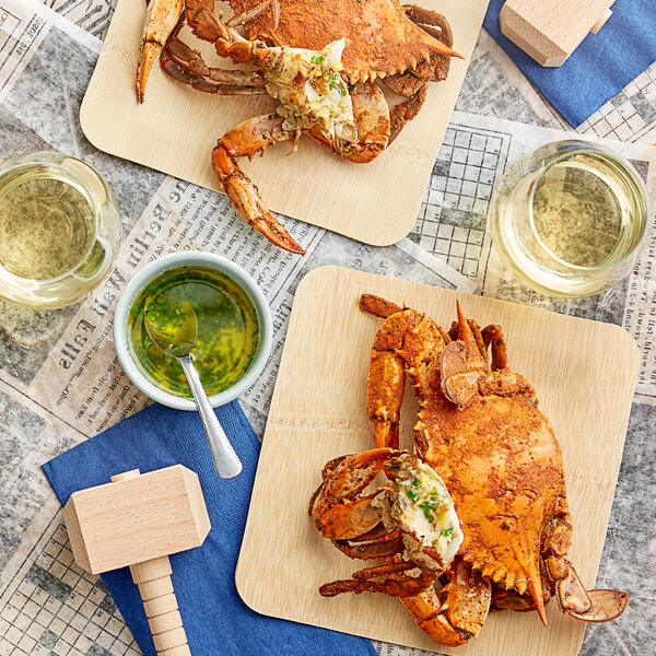 A wooden table with a newspaper and a wooden board with large seasoned steamed female crabs on it.