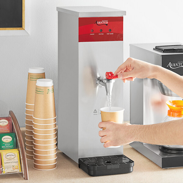 A person pouring water from a faucet into an Avantco hot water dispenser.