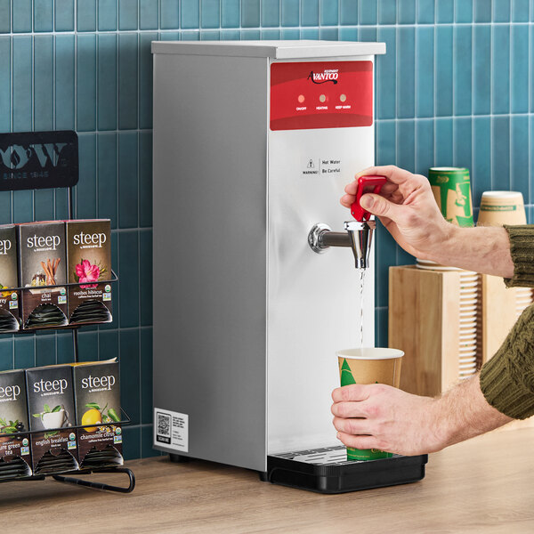 A stainless steel hot water dispenser with a red control panel, dispensing hot water into a paper cup.