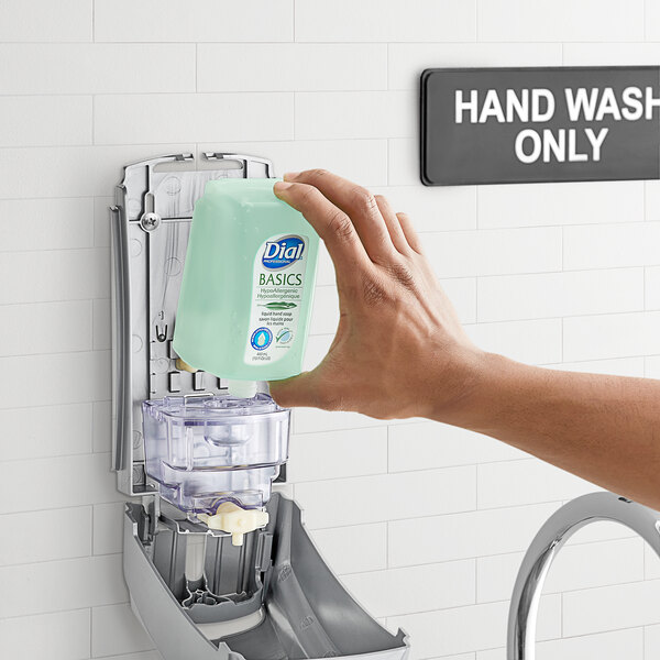 A hand holding a bottle of Dial Versa Professional hypoallergenic liquid hand soap.