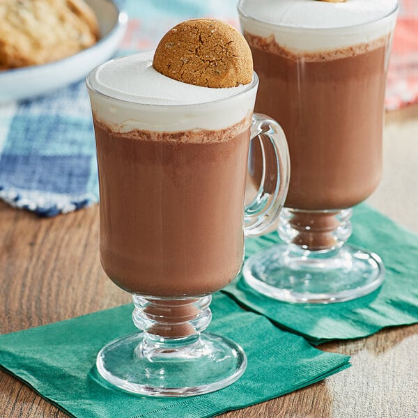 Two glasses of gingerbread cookie hot chocolate with a cookie on top.