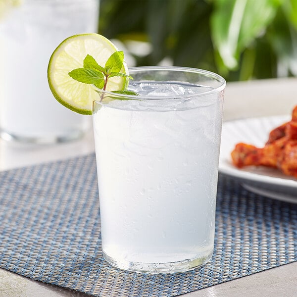 A Bodega by Bormioli Rocco Maxi Tumbler of water with ice and a lime wedge.