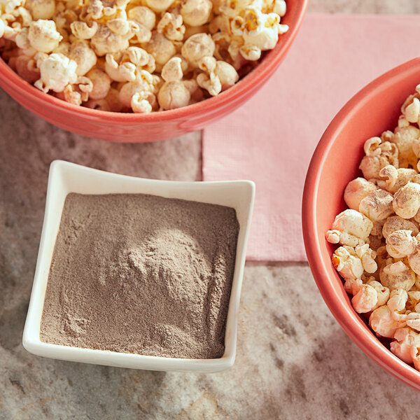 A white square bowl of popcorn with brown powder on it.