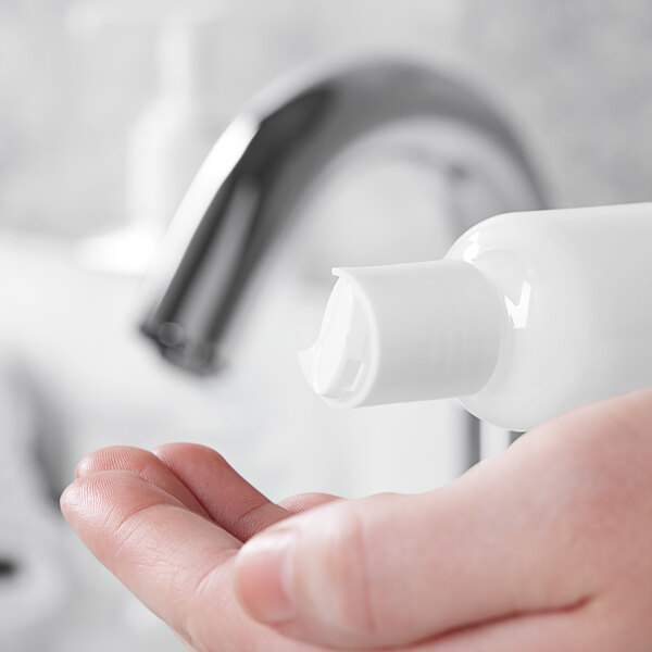 A person using a 20/410 white unlined disc top lid to pour hand soap onto their hand.