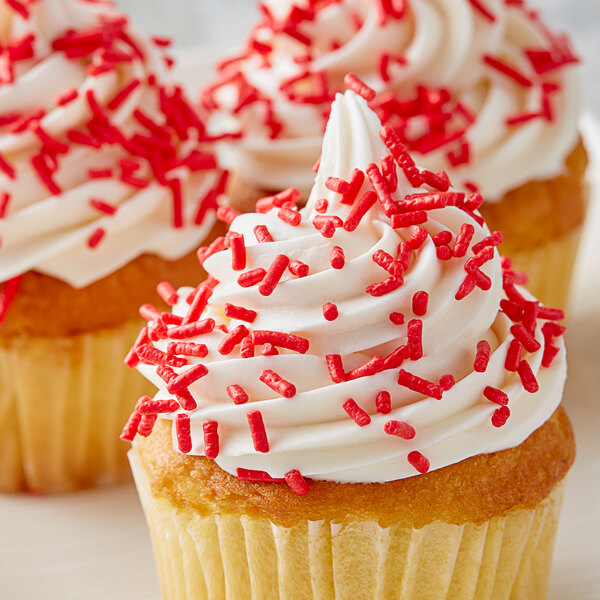 A cupcake with white frosting and Bake-Stable Red Sprinkles.