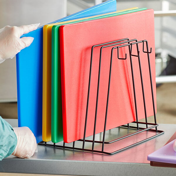 A person in a lab coat using a black wire cutting board storage rack.