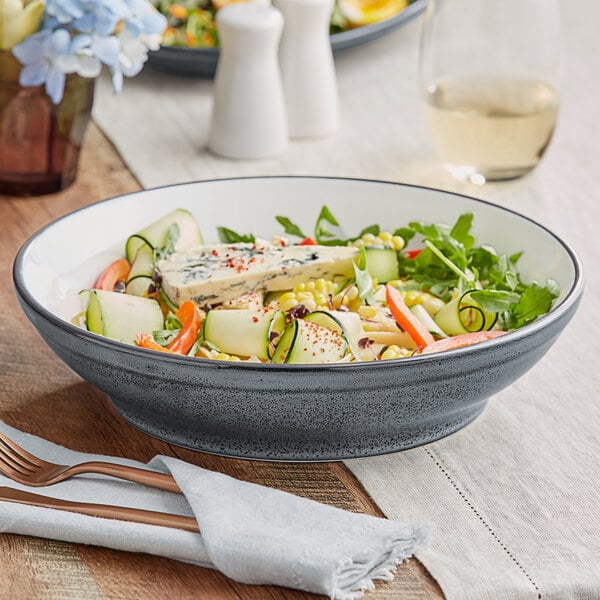 A bowl of salad with blue cheese and vegetables in an Acopa midnight blue stoneware bowl on a table.