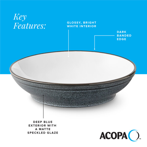 A stoneware pasta bowl with a glossy white interior, dark banded edge, and a deep blue matte speckled exterior.