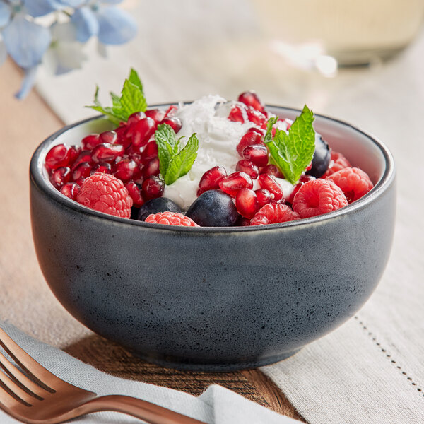 A bowl of berries and cream in an Acopa midnight blue stoneware bowl with a spoon.