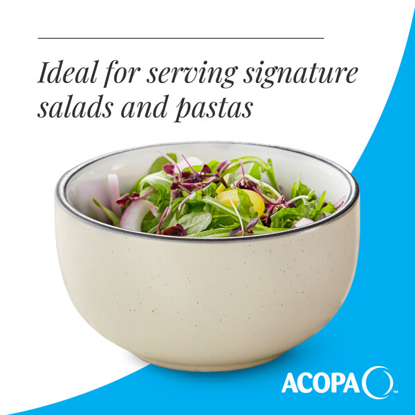 A cream white matte stoneware bowl filled with salad greens.