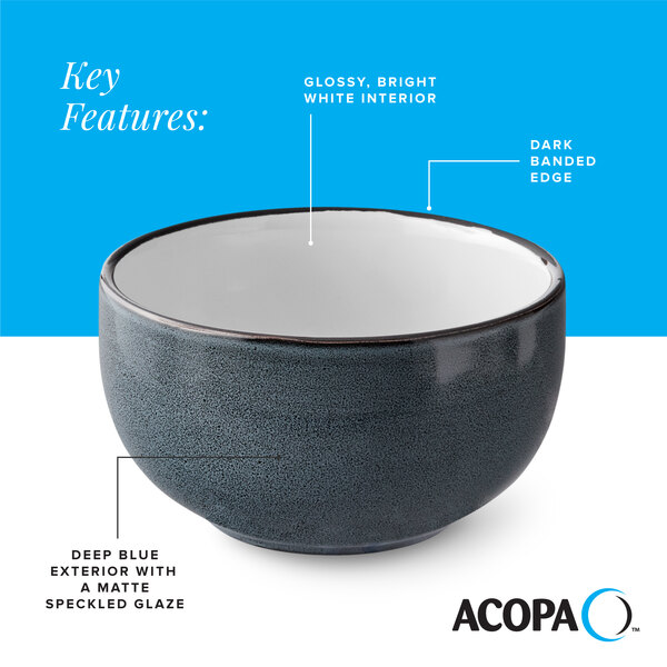 A stoneware bowl with a deep blue matte speckled exterior, glossy white interior, and a dark banded edge.