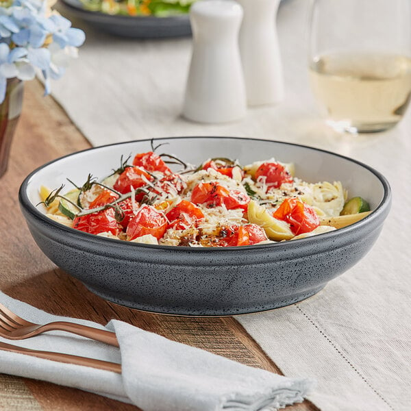 A bowl of pasta with tomatoes and cheese in a blue stoneware bowl.