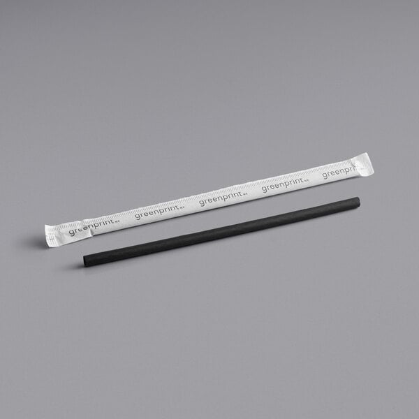 A black plastic straw in a white wrapper with black writing.