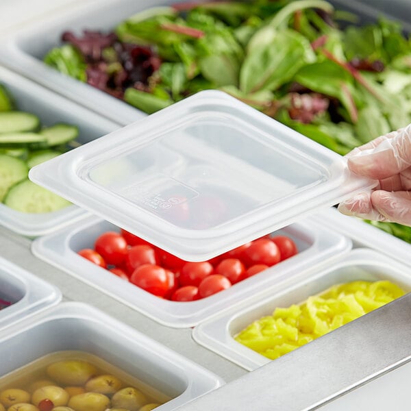 A hand securing a Vigor translucent polypropylene lid on a container of food.