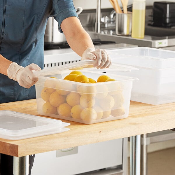A woman using a Vigor translucent polypropylene food pan to hold lemons.