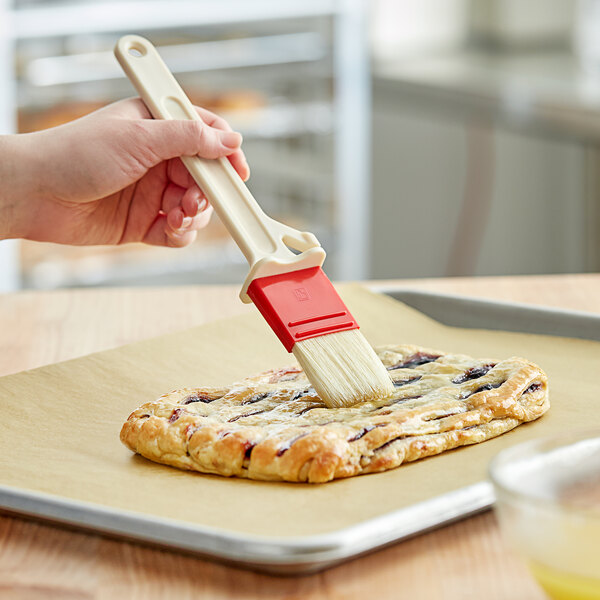 A person using a Choice pastry brush to baste a pastry.