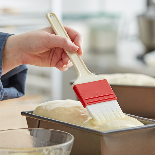 A hand using a Choice pastry brush to brush a loaf of bread.
