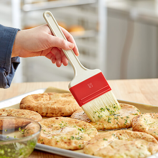A person using a Choice natural bristle pastry / basting brush to brush food.
