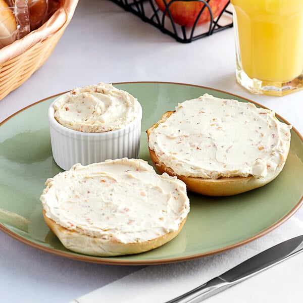 A plate with a bagel and Philadelphia Garden Vegetable Cream Cheese spread on it.
