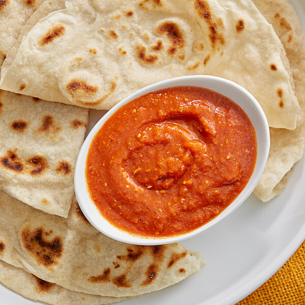 A plate of tortillas with a bowl of red sauce on it.