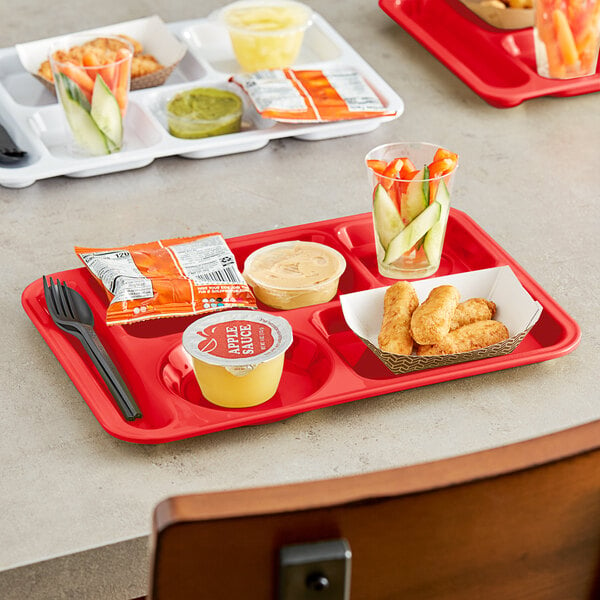 A Choice left handed red melamine compartment tray with food and a cup of vegetables on it.