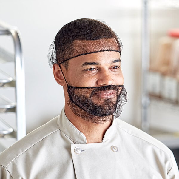 A man in a chef's uniform wearing a brown hairnet over his head.